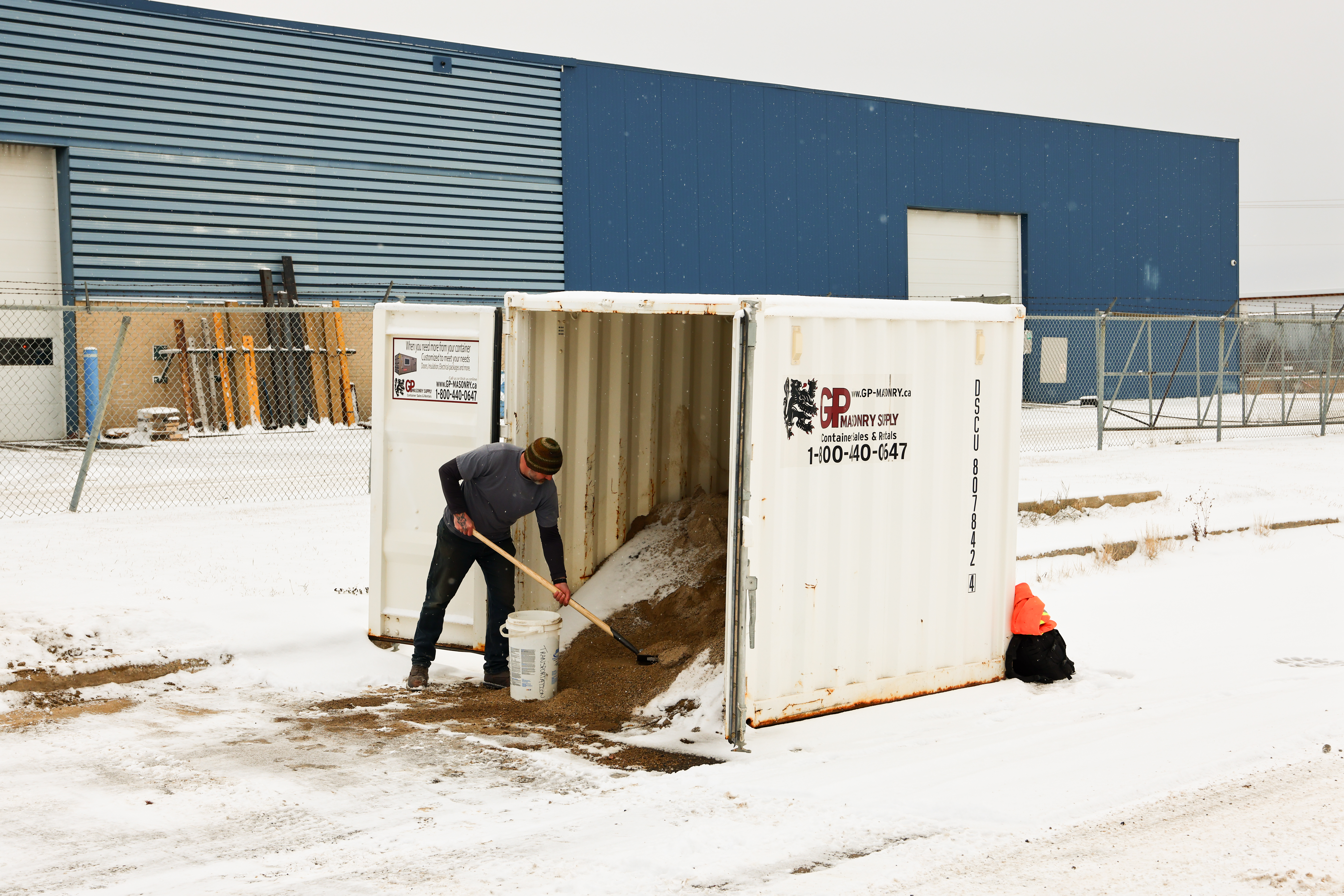 Image of person collecting sand from a community sandbox used for winter traction and accessibility