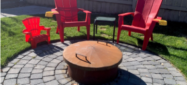 Firepit in a back yard with two red chairs 