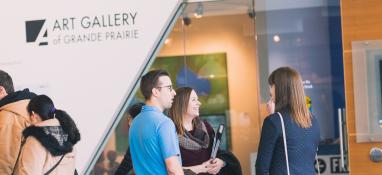 Photo of Art Gallery of Grande Prairie entrance with people standing out front talking candidly. 